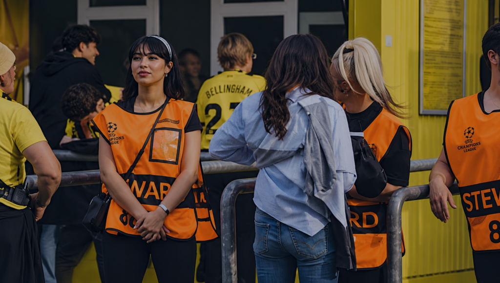 Event staff wearing orange safety vests assisting attendees at a live event